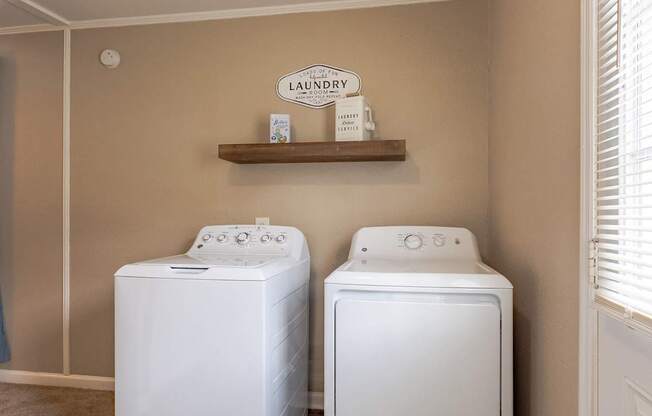 Two white front load washing machines in a laundry room.