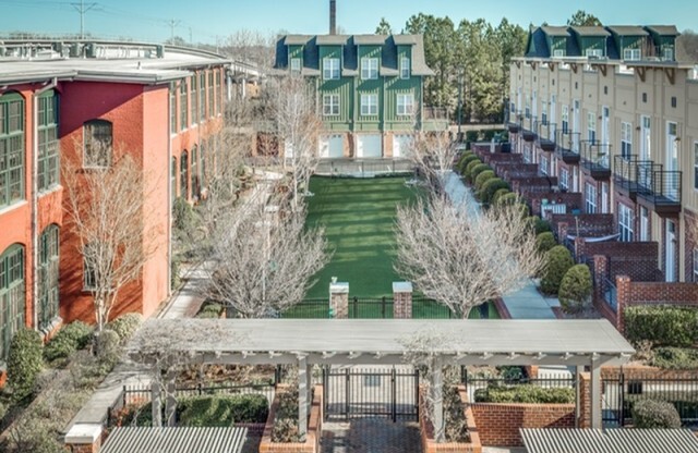 View of Townhomes, Showing Dog Park, Alpha Mill Building Exteriors, and Attached Garages at Alpha Mill Apartments