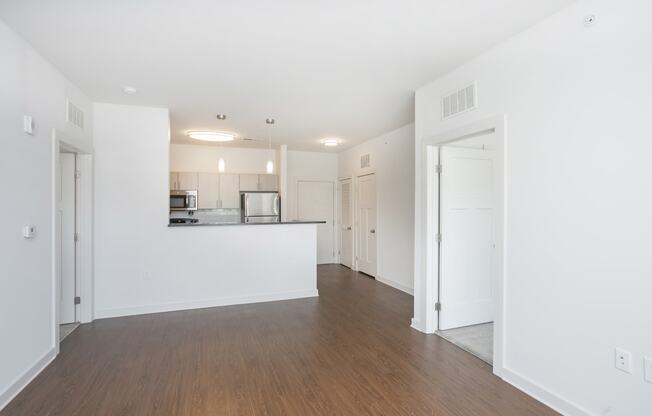 a bedroom with a medium sized bed and a kitchen in the background