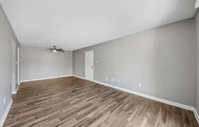 an empty living room with wood flooring and a ceiling fan