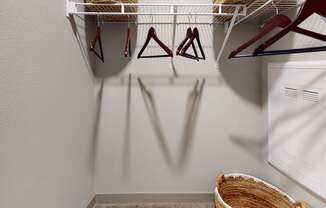 a walk in closet with a white closet organizer and a basket on the floor