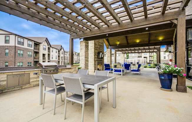 A patio with a table and chairs under a wooden pergola.