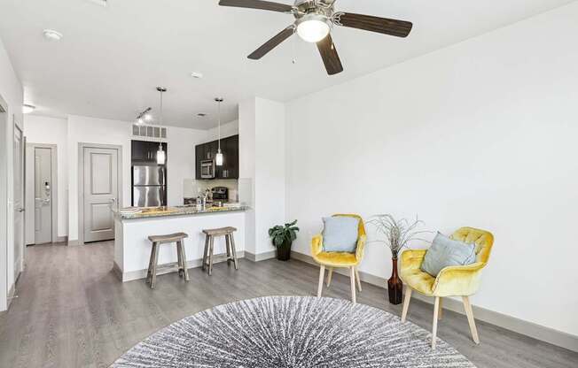 An open living room with a ceiling fan and grey rug at GreenVue Apartments in Richardson, TX