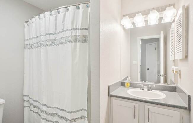 A white bathroom with a shower curtain and a sink.