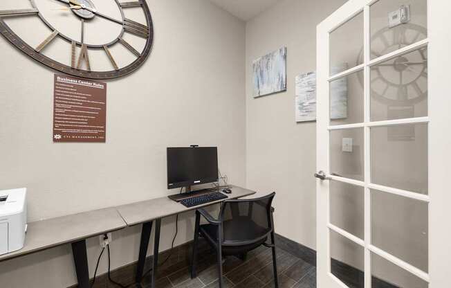 A business center with a desk, a computer, and a clock on the wall at Clackamas Trails Apartments, Oregon, 97222