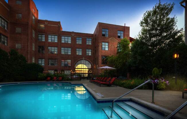 A large red brick building with a pool in front.