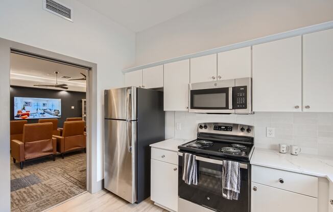 a kitchen with white cabinets and stainless steel appliances and a refrigerator