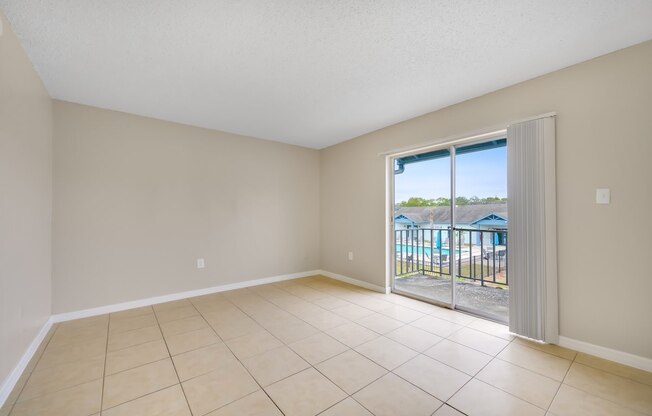 an empty living room with a sliding glass door to a balcony