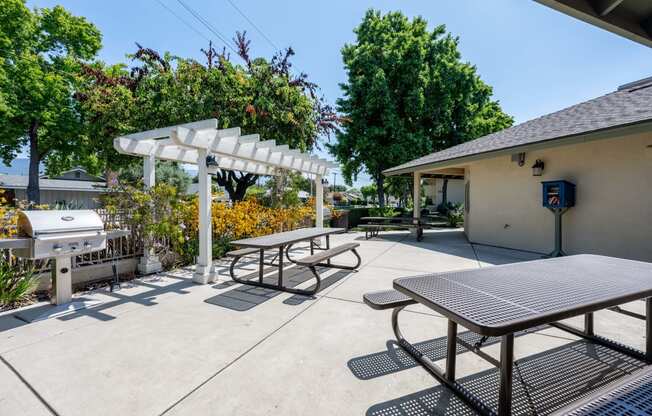 a picnic table with a grill and a pergola at the enclave at woodbridge apartments