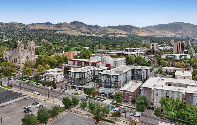 A cityscape with a church in the foreground and mountains in the background.