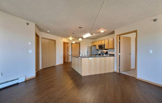 a living room and kitchen with wood floors. Fargo, ND East Bridge Apartments