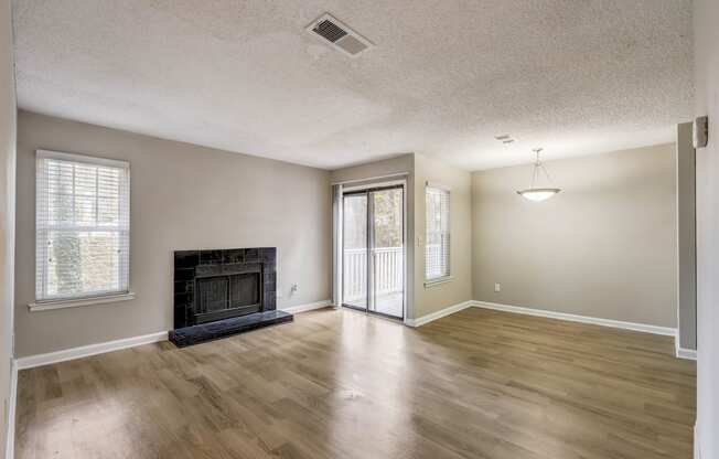 a spacious living room with hardwood floors and black fireplace with glass door to private balcony at Veridian at Sandy Springs apartments