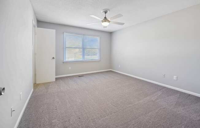 an empty living room with a ceiling fan and a window