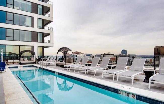 a swimming pool with white lounge chairs and a building in the background at The Boro, Tysons, VA