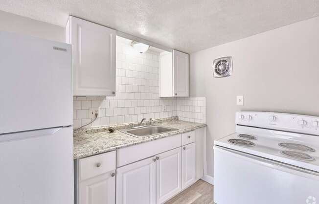 Kitchen with white appliances and wooden cabinets at Fay Street Apartments, Winchester, VA 22601