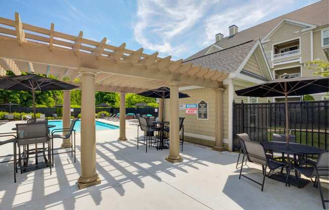 a patio with tables and chairs overlooking a swimming pool