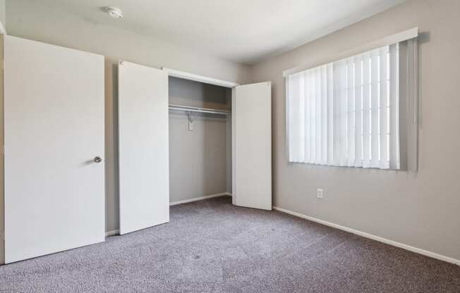 an empty bedroom with a closet and a window