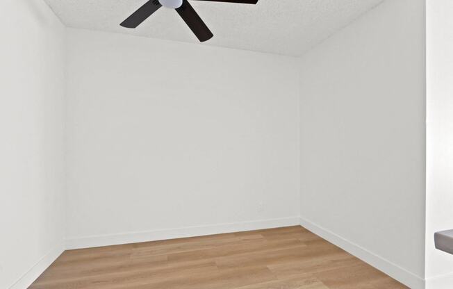 a room with white walls and a ceiling fan