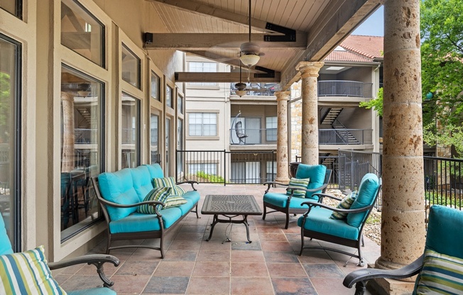 a covered patio with blue chairs and a coffee table at Waters Edge Apartment Homes, Georgetown
