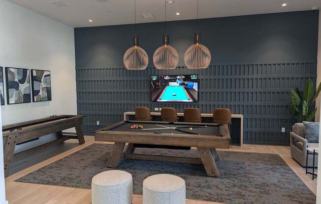 A room with a pool table and a TV mounted on the wall.