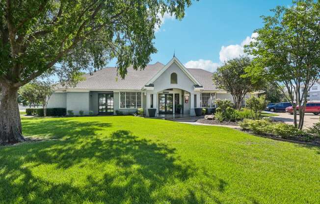 the front of a house with a lawn and trees