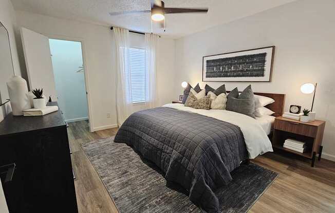 A bedroom with a bed, nightstand, and a ceiling fan.