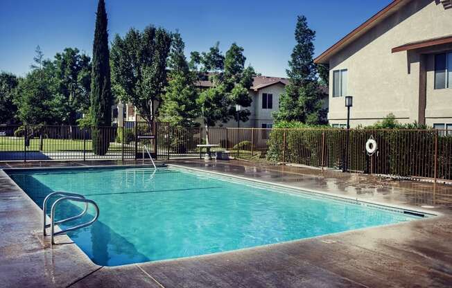 a pool with a fence around it and a house in the background