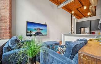 a living room with couches and a kitchen with a tv on the wall