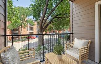 a balcony with a tree and two chairs and a table