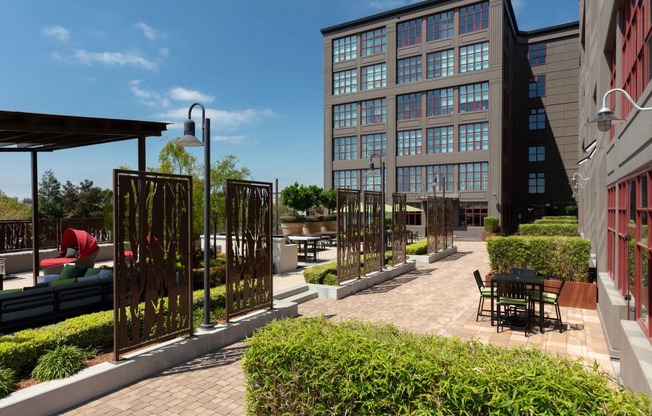 a courtyard with tables and chairs and a building in the background