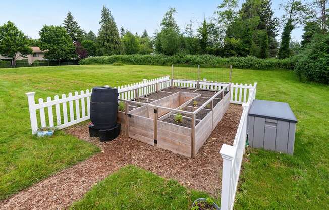 a garden with a raised garden bed and a fence at Eagles Landing Apartments, Everett, 98204