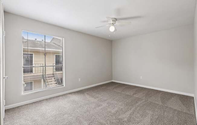 A room with a carpeted floor and a ceiling fan.