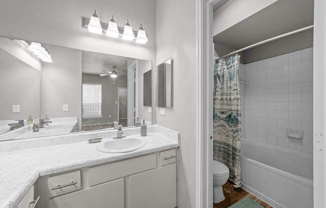 A bathroom with a sink, mirror, and shower.