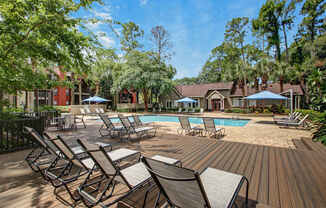 A pool surrounded by chairs and trees.