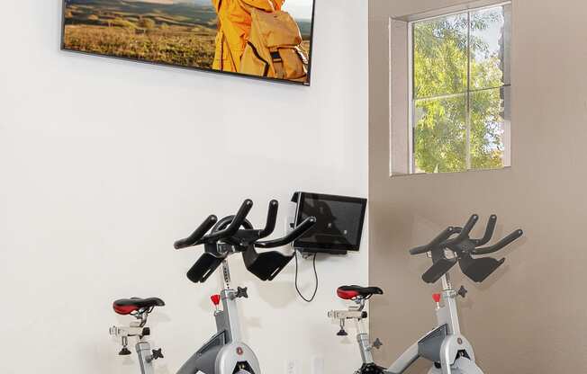 an indoor gym with three exercise bikes and a picture of a man with his arms