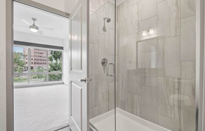 A white bathroom with a glass shower door and a window.