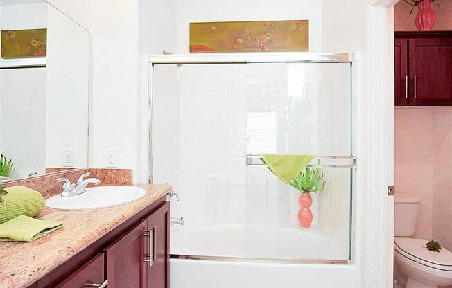 A bathroom with a sink, mirror, and shower.
