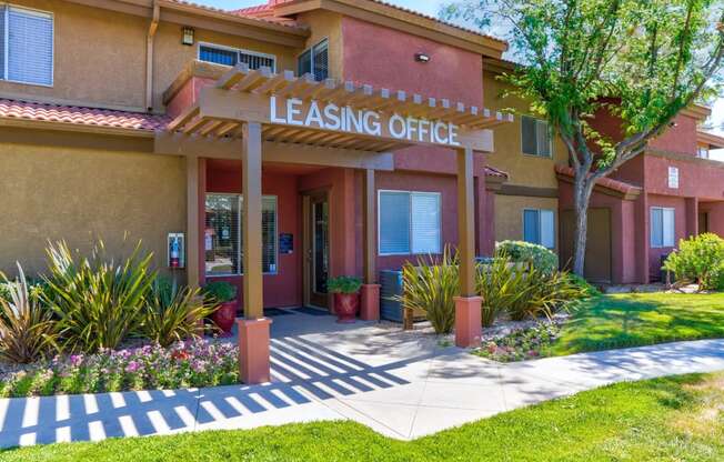 a building with a leasing office and a tree in front of it