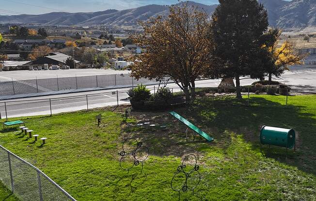 A park with a green trash can and a green bench.