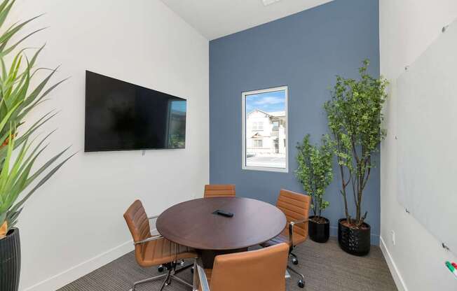 A conference room with a table, chairs, and a television.
