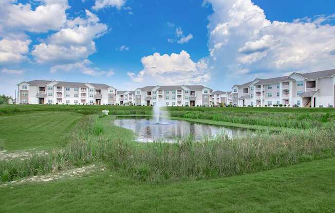A large white building with a pond in front of it.