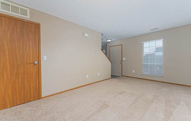 A room with a carpeted floor and a wooden door.