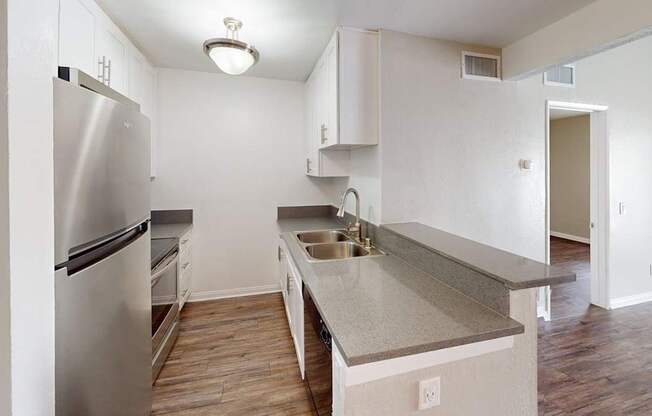 A kitchen with a stainless steel refrigerator and a countertop with a sink.