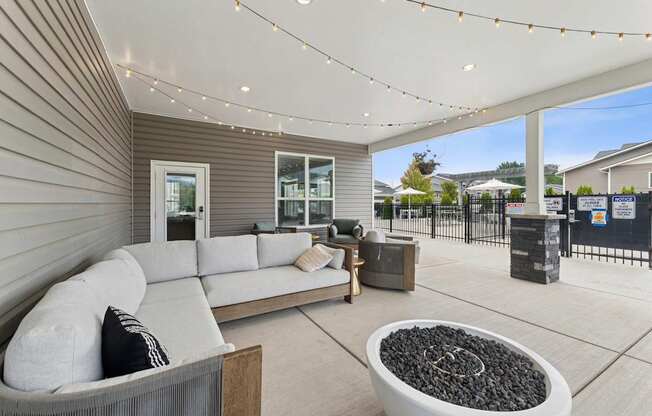 A modern outdoor living space with a grey sofa and a fire pit.