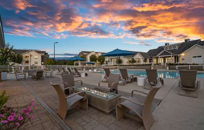 a swimming pool with chairs and tables at dusk