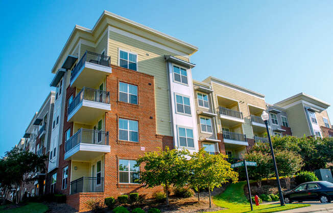 A multi-story apartment building with balconies and a clear blue sky above.
