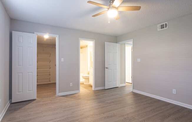 an empty living room with wood floors and a ceiling fan