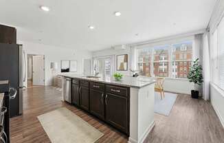 A kitchen with dark wood floors and white walls.