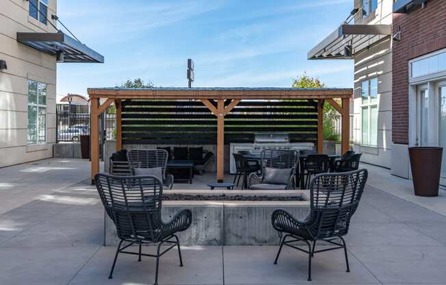 a patio with a fire pit and chairs and a wooden pergola