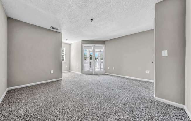 an empty living room with gray walls and a door to a balcony